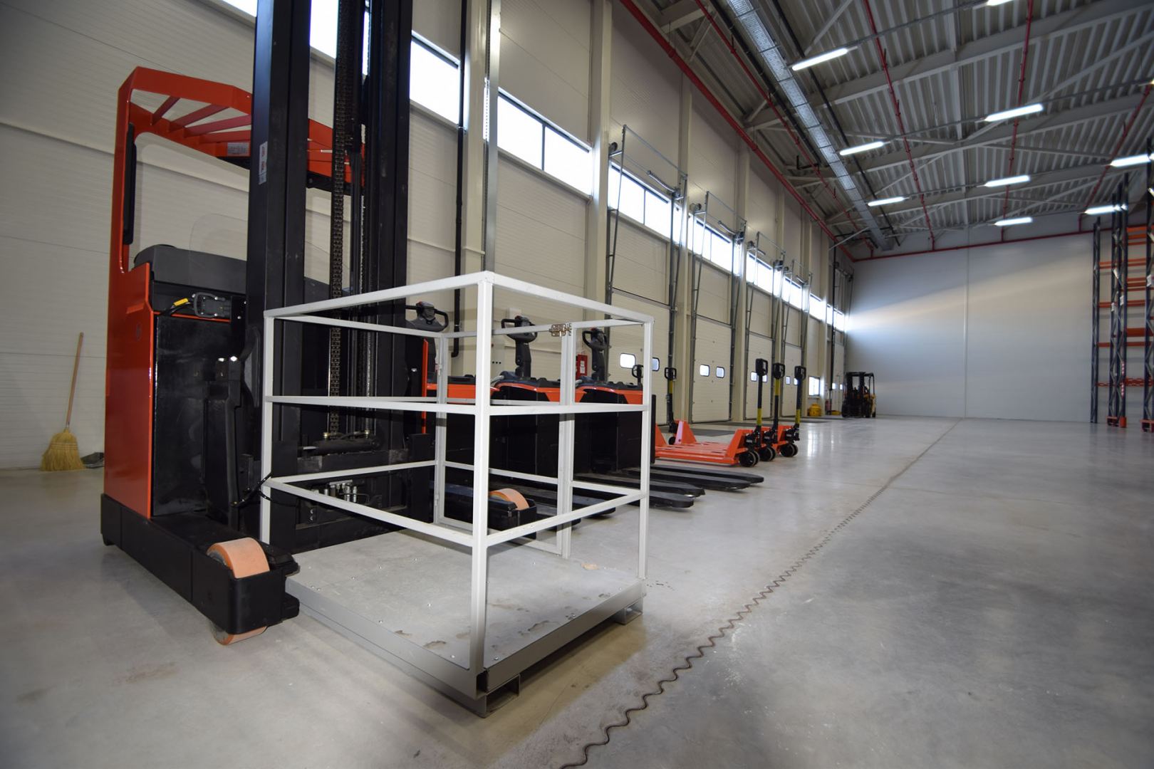 Modern orange and black forklifts positioned in a spacious industrial warehouse near loading bays